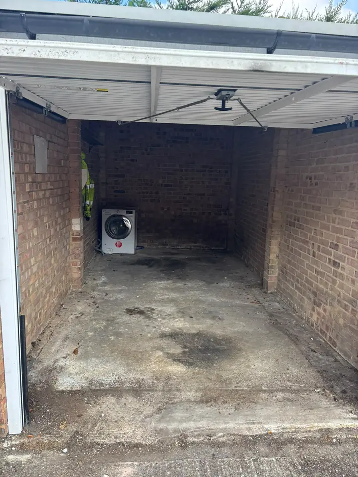Garage after the loose contents were cleared; a washing machine remains.